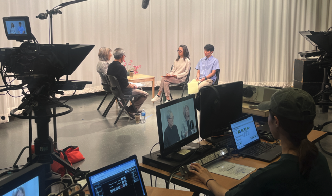 A student monitors a screen and multiple cameras with a TV recording studio in front of her