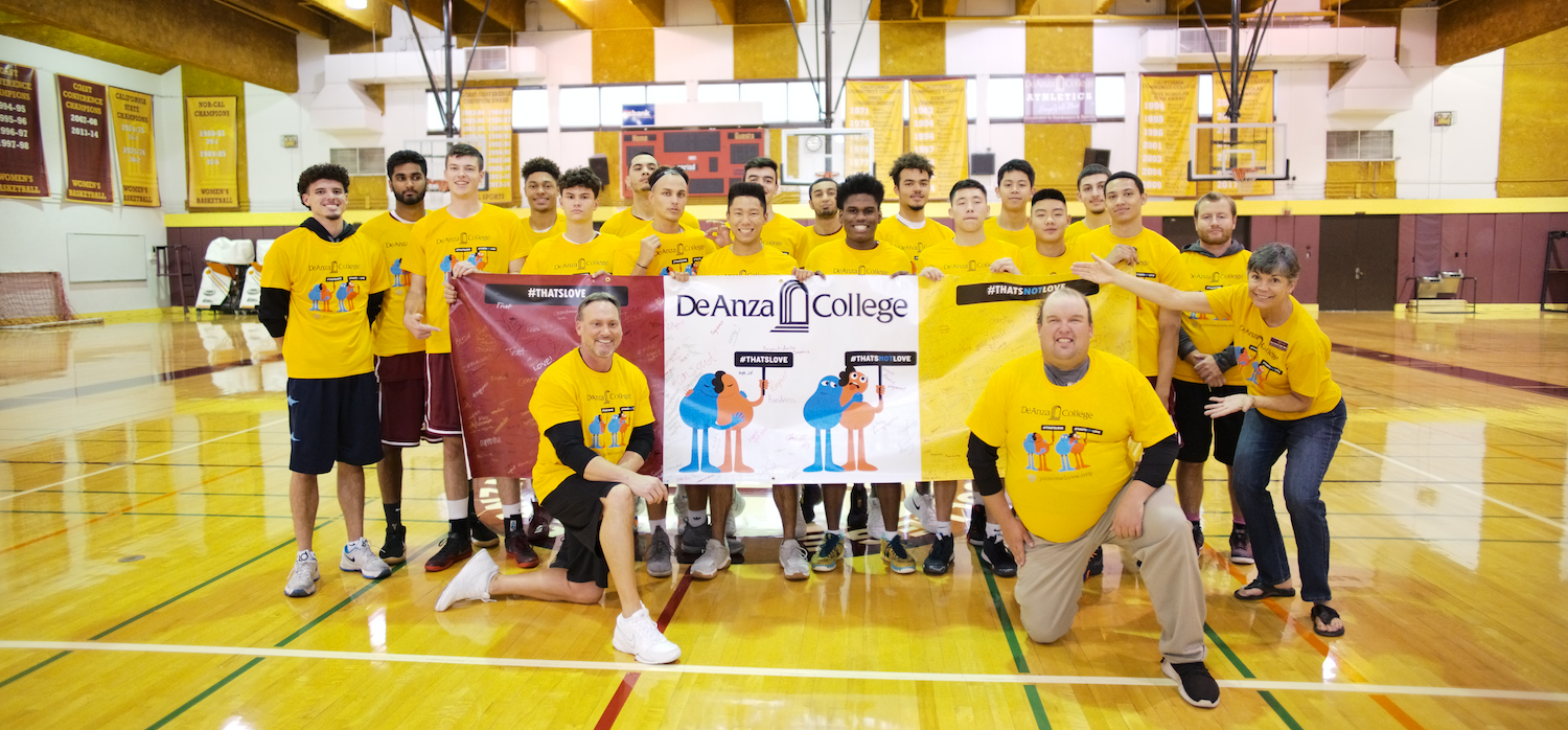 men's basketball team with banner against relationship violence