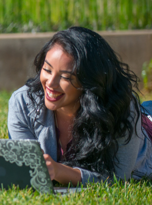 young woman using laptop computer while prone on lawn