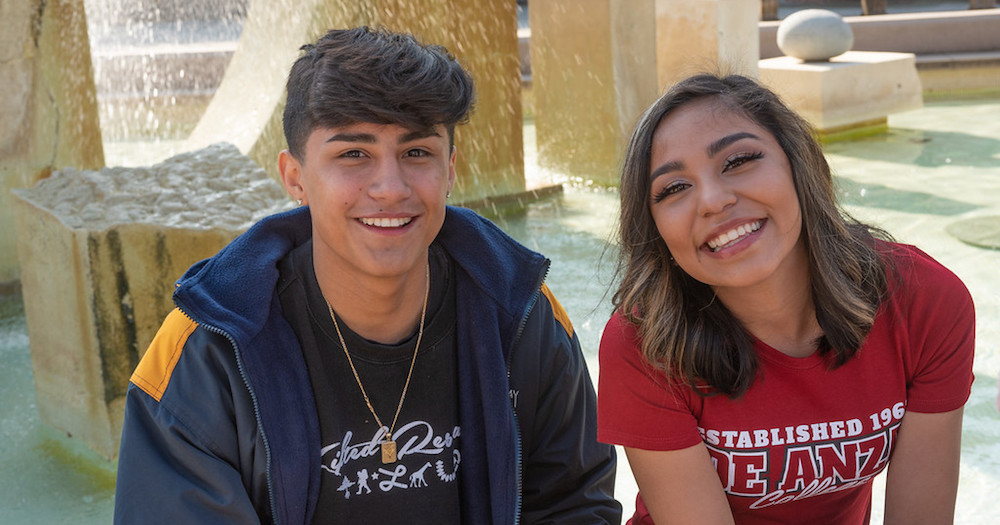 young man and woman sitting by fountain