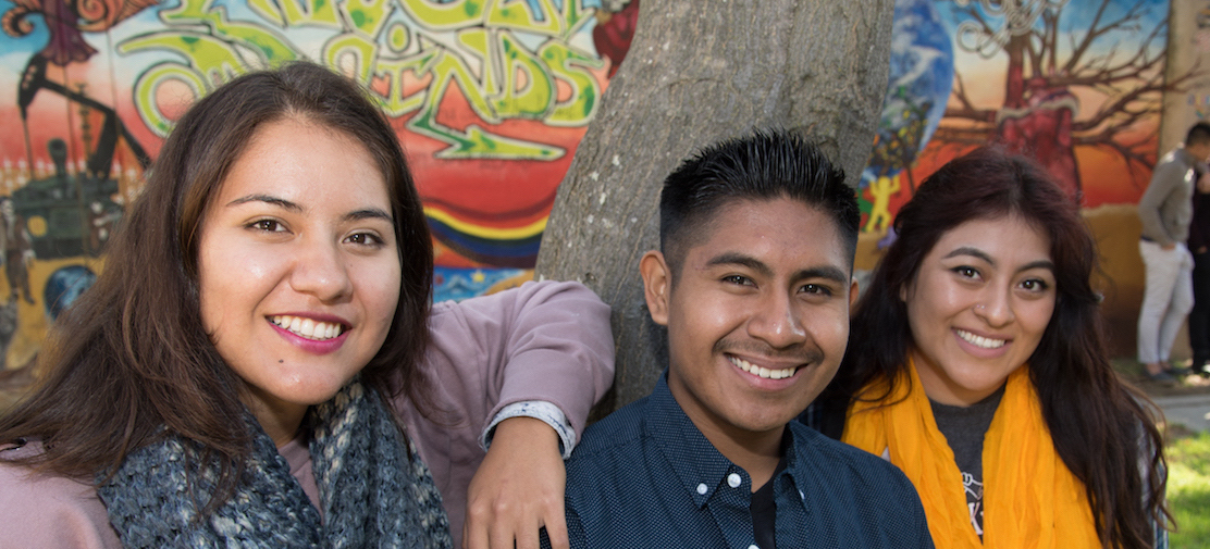 three students in front of tree