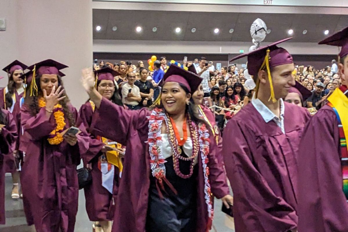 student waving in line of grads