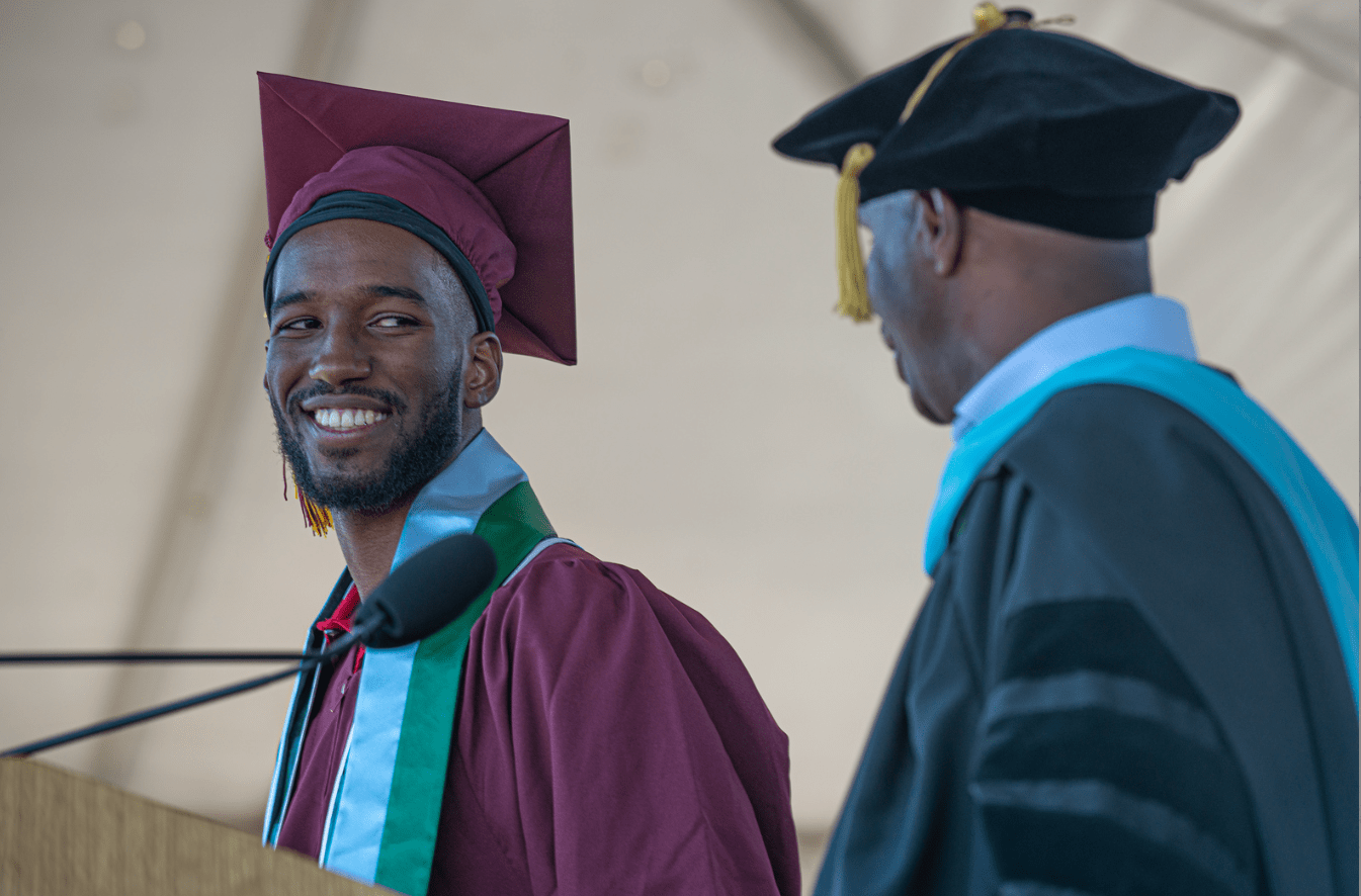 student in grad cap on stage with vice president